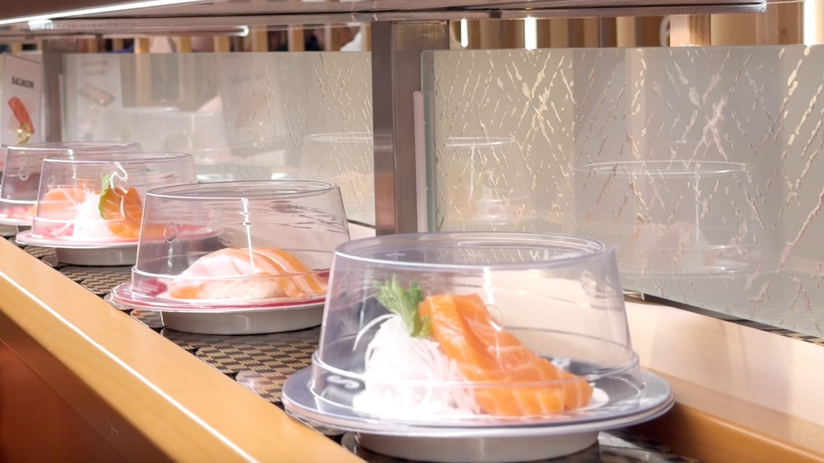 Salmon nigiri plates lined up on the revolving belt at Makoto Staten Island