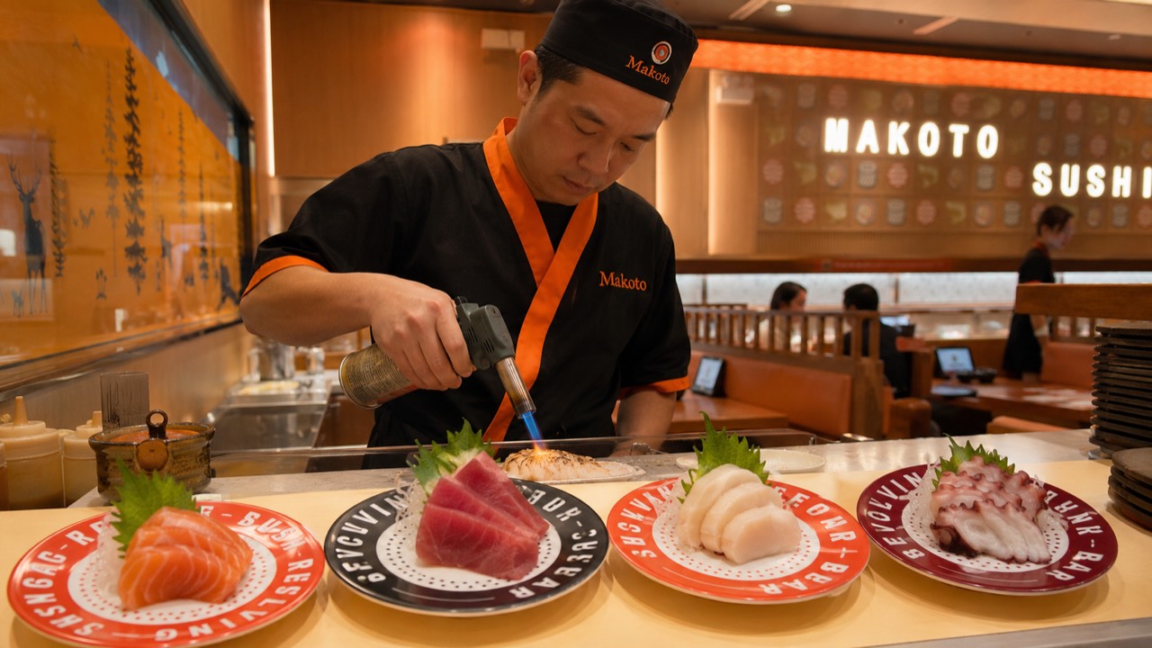 Makoto chef torch-searing sashimi plates of salmon tuna and white fish at the sushi bar in Staten Island