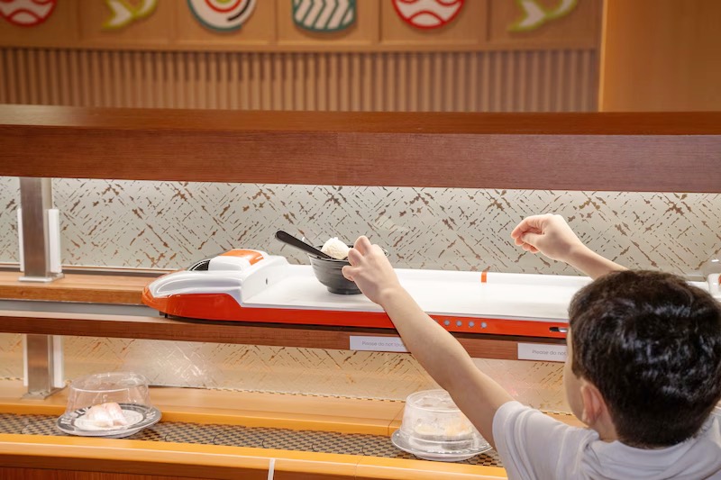 Child reaching for a sushi plate delivered by the bullet-train express lane at Makoto revolving sushi bar in Staten Island
