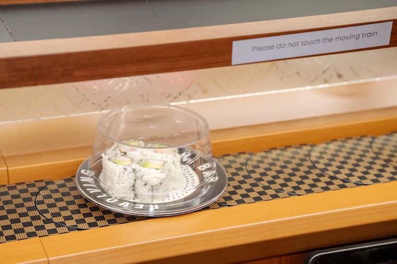 Dome-covered sushi plate gliding along the conveyor belt at Makoto Staten Island