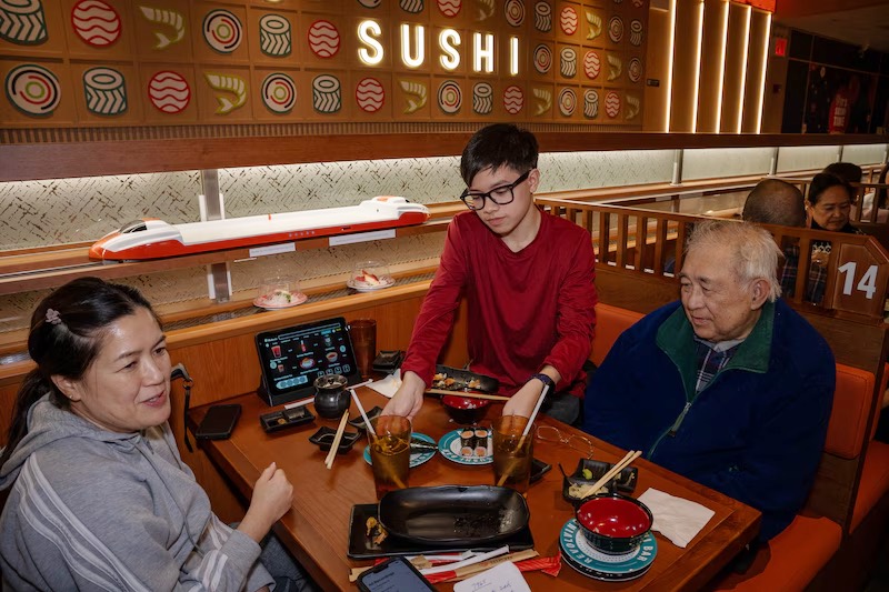 Three generations sharing a sushi dinner under the Makoto Sushi sign in Staten Island