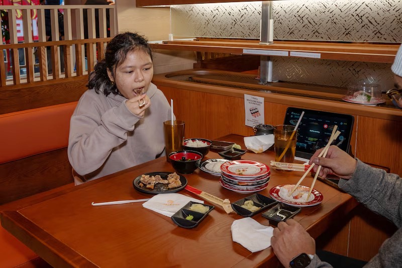 Guest enjoying a colorful spread of sushi plates in a booth at Makoto Staten Island
