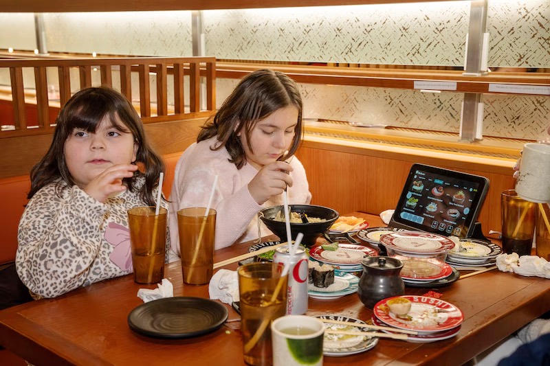 Two children enjoying sushi and drinks in a booth at Makoto Staten Island