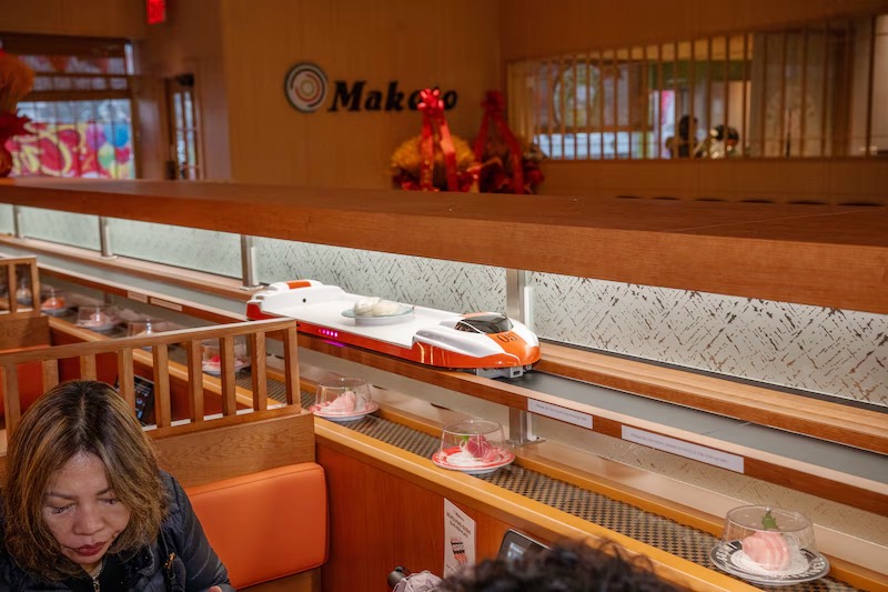 Plates of sushi circling beneath the Makoto sign on the conveyor belt in Staten Island