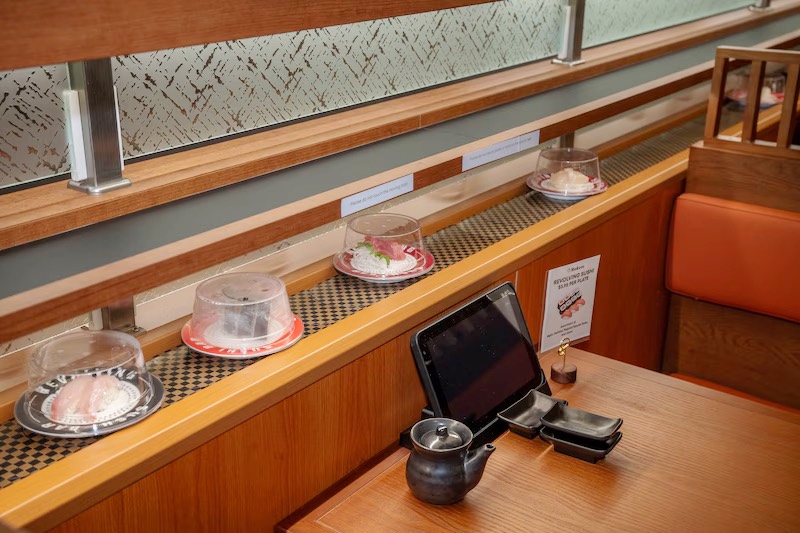Touchscreen ordering tablet beside the sushi belt at a Makoto booth in Staten Island