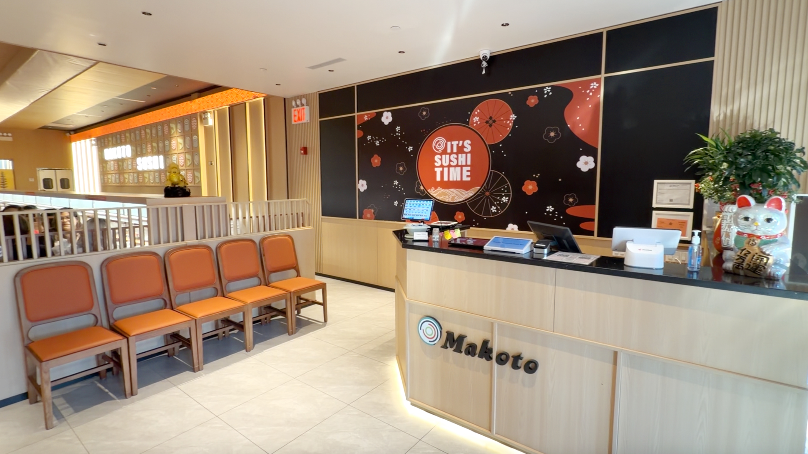 Warm Makoto reception lobby with It's Sushi Time wall and maneki-neko welcoming guests in Staten Island
