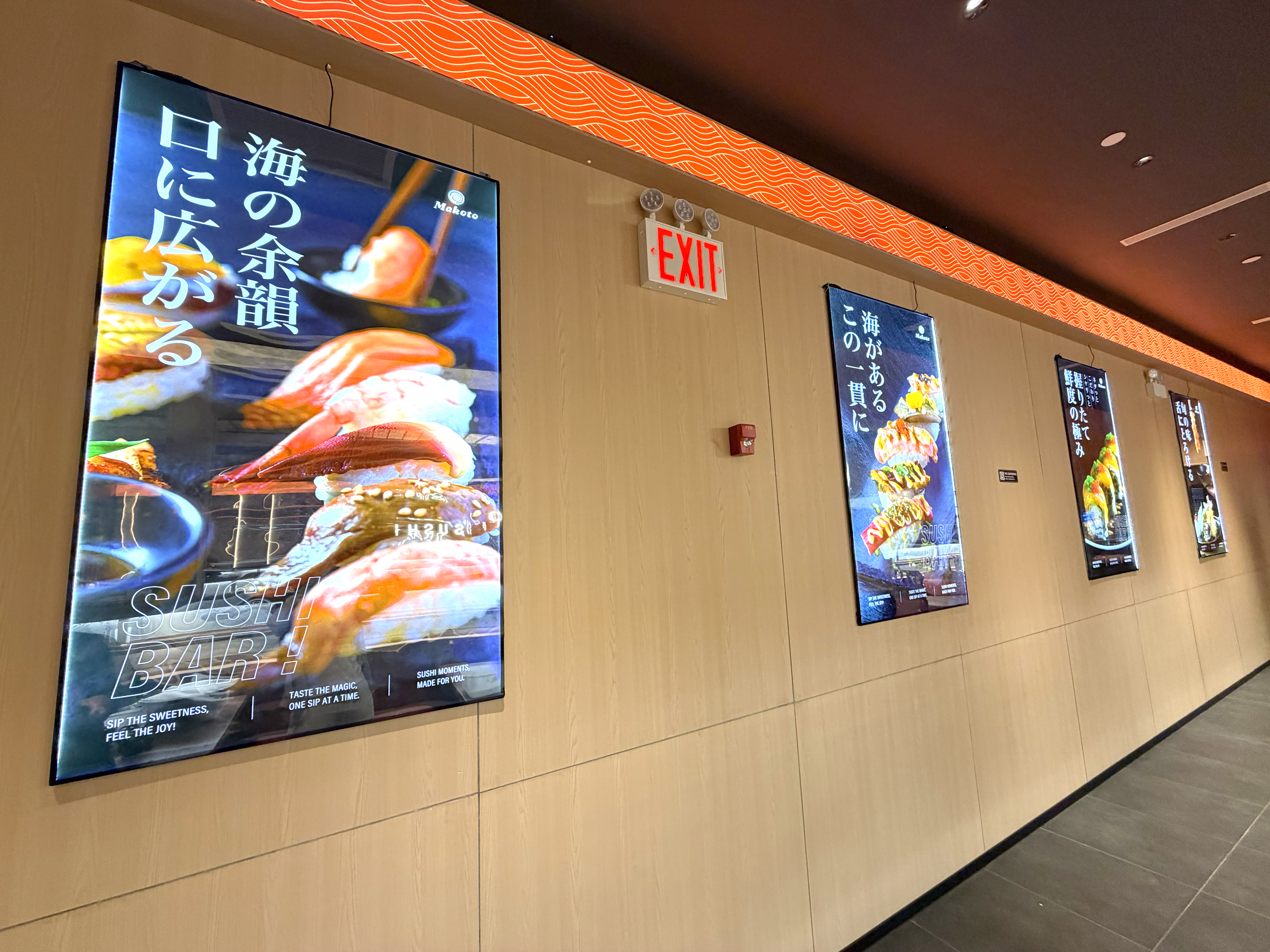 Wall of glowing Japanese sushi menu posters showcasing Makoto's variety in Staten Island